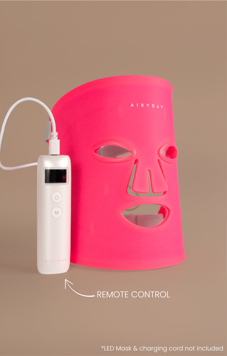 Pink LED face mask with remote control on a brown background